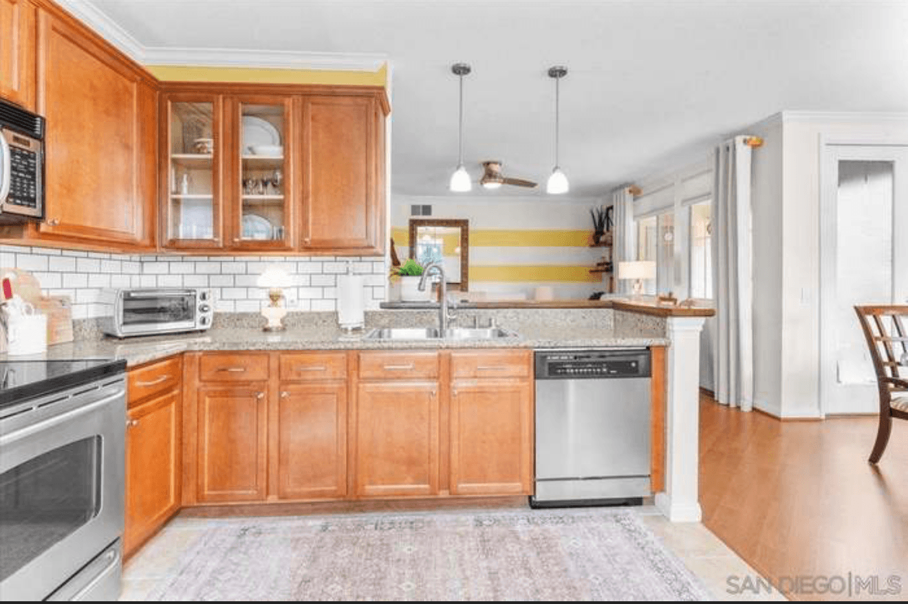 Modern kitchen with wood cabinets, white subway tile backsplash, granite countertops, and stainless steel appliances.